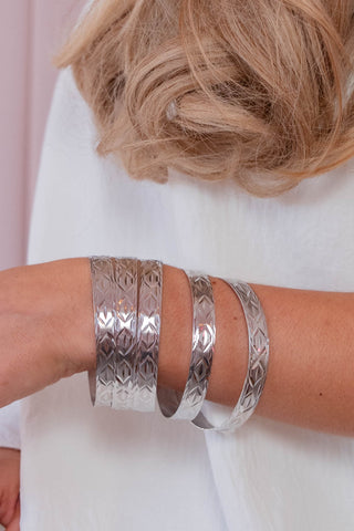 Silver bangles on a person's wrist with a blurred background
